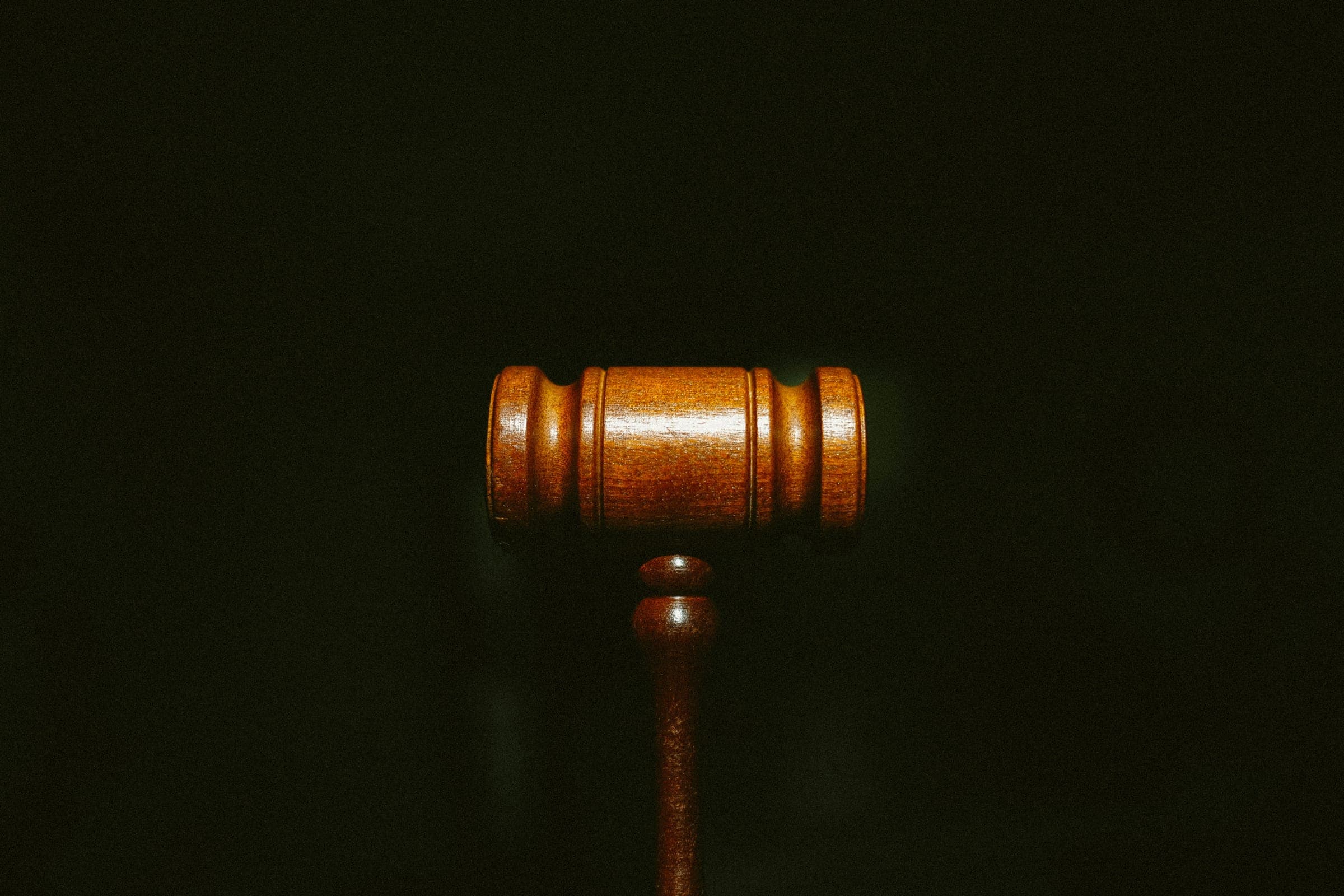A wooden judge's gavel lit against a dark background